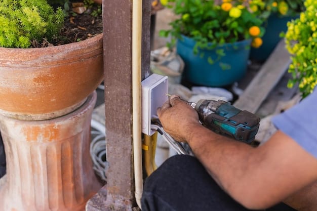 A homeowner installing a smart sprinkler controller on a wall, with tools like a screwdriver and wire stripper nearby. The controller is partially installed, with various colored wires connected to the terminals.