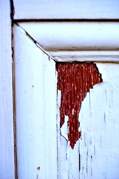 A close-up shot of a poorly insulated attic hatch, showing gaps around the edges where air can leak through. Dust and cobwebs are visible around the hatch, indicating lack of sealing. The focus should be on the contrast between the insulated attic space and the uninsulated hatch.