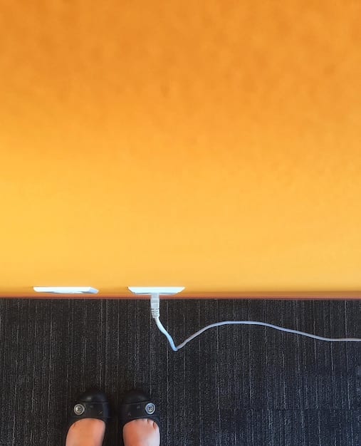 A person unplugging a phone charger from a wall outlet, with a focus on the electrical outlet and the charger. The background is blurred to draw attention to the action of unplugging.