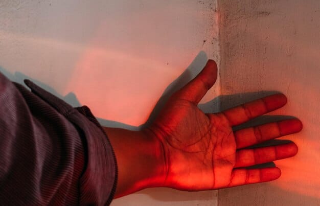 Close-up shot of a hand holding a thermal leak detector, showing a red spot indicating a significant air leak around a window frame.