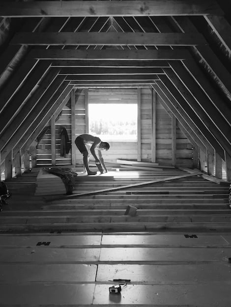 An attic filled with new fiberglass insulation, showing the depth and coverage. A worker is visible in the background, ensuring proper installation.