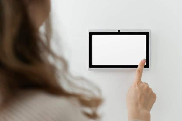 A close-up of a hand dusting a smart thermostat display mounted on a wall. The image focuses on the act of cleaning to emphasize the importance of keeping smart home devices free of dust and debris for optimal performance.